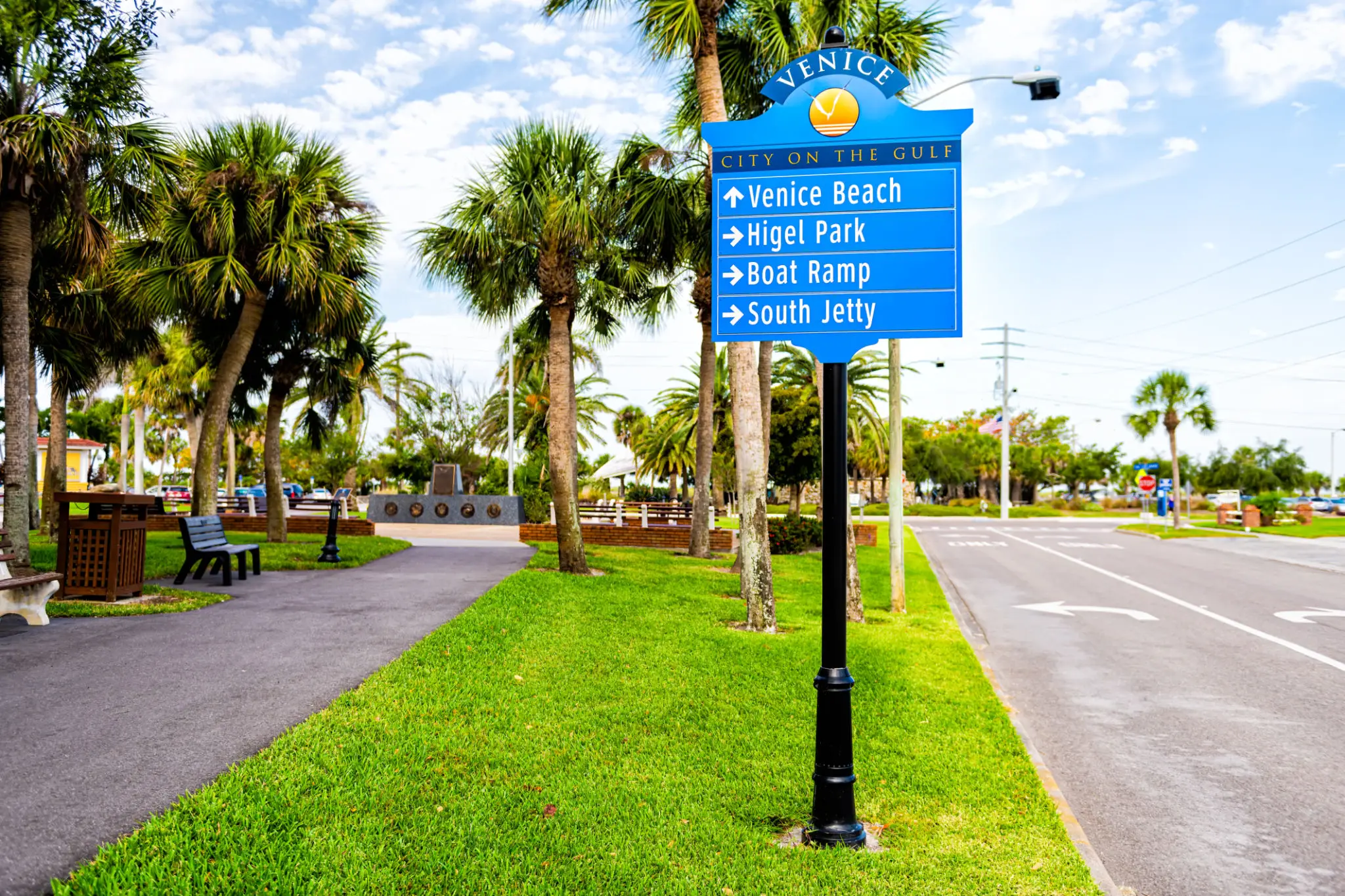 Directional signpost on a sunny street with palm trees.
