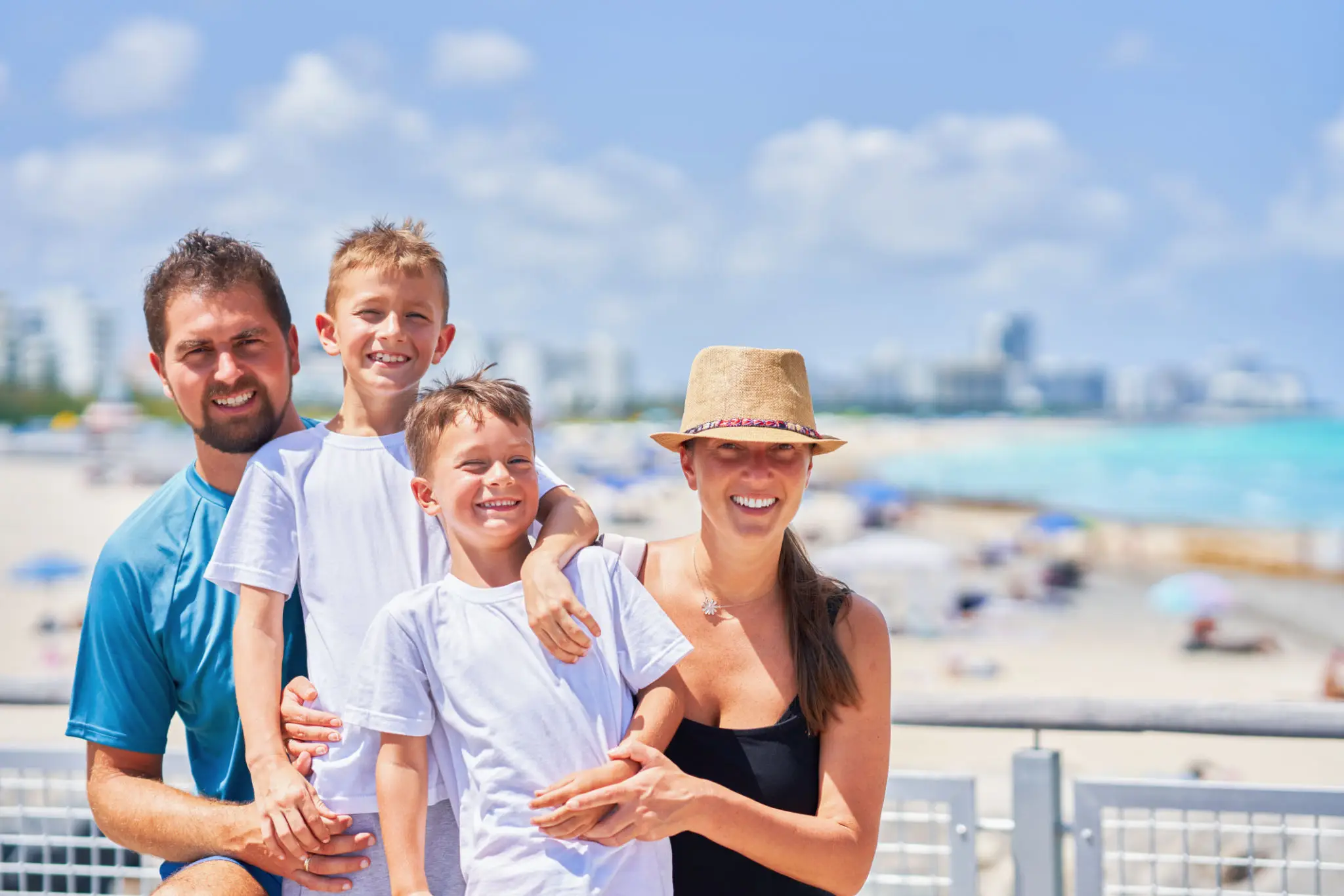 Happy family of four enjoying a sunny day at the beach.