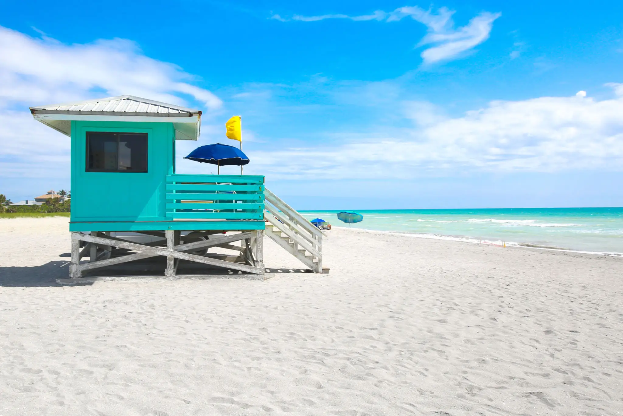 A lifeguard hut on a sunny, sandy beach with clear blue skies.