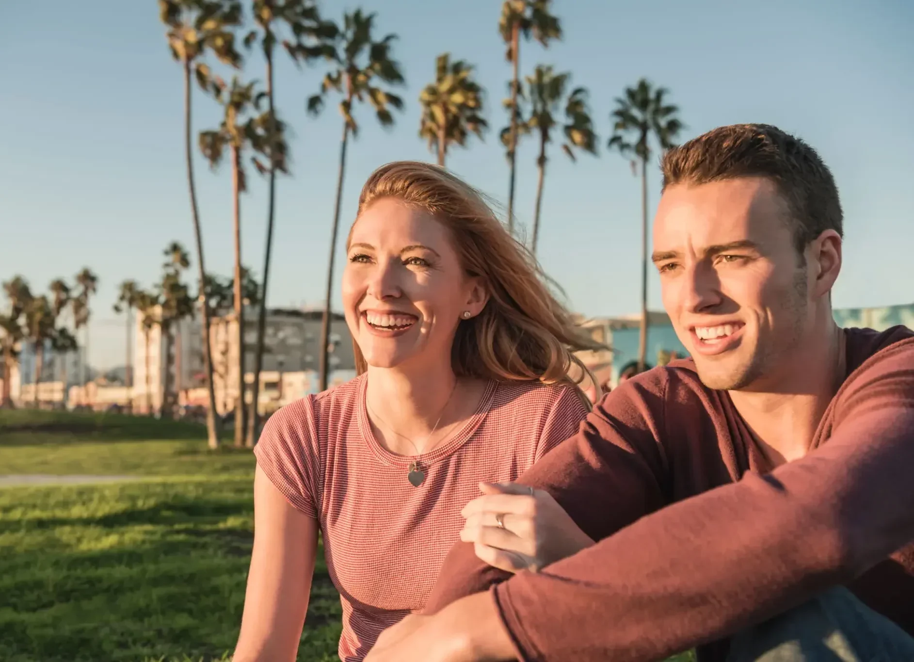 A happy couple sitting outdoors with palm trees in the background.